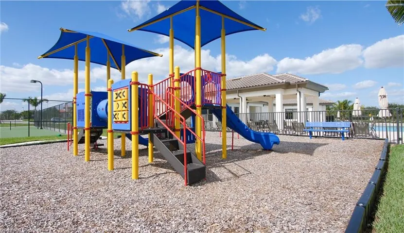 Community playground featuring a composite play structure with slides and shaded canopies over wood chip surfacing