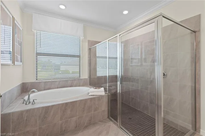 Spa-inspired bathroom featuring a built-in soaking tub, a separate glass-enclosed shower with tiled walls, and ceramic tile flooring