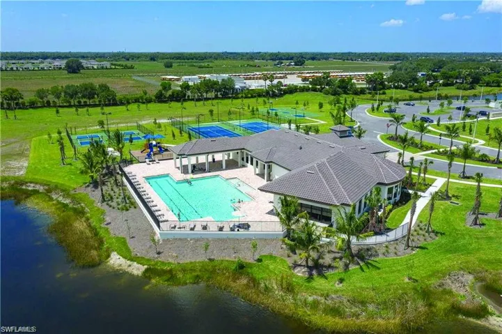Community clubhouse featuring a large swimming pool, covered outdoor lounge area, pickleball courts, tennis courts, and a playground