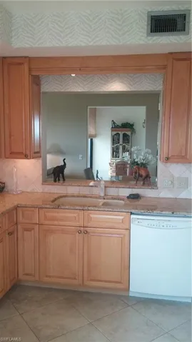 Kitchen featuring tasteful backsplash, dishwashing machine, light stone counters, and light tile patterned flooring