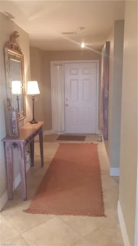Hall featuring baseboards and light tile patterned flooring