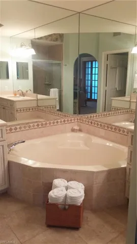 Full bath featuring a garden tub, light tile patterned floors, and vanity