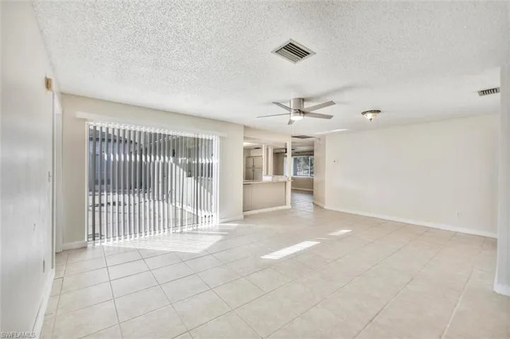 Unfurnished room with a textured ceiling, a ceiling fan, and light tile patterned flooring