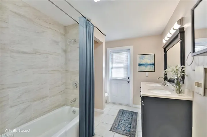 Virtually Staged Bathroom with shower / tub combo, double vanity, and light tile patterned floors