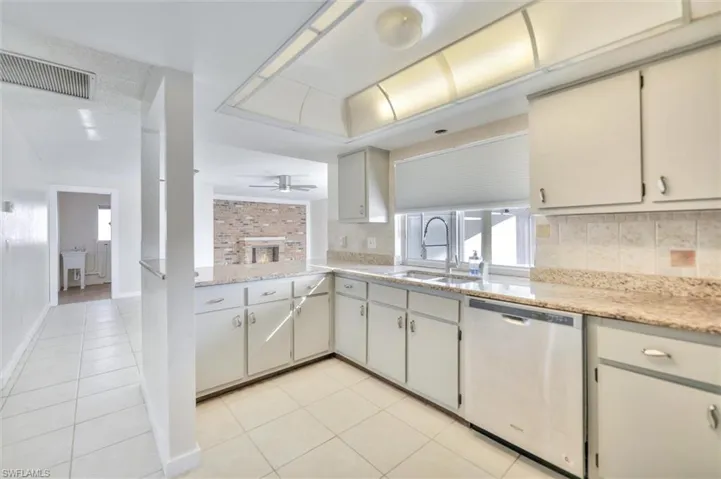 Kitchen featuring dishwasher, tasteful backsplash, light stone counters, and plenty of natural light