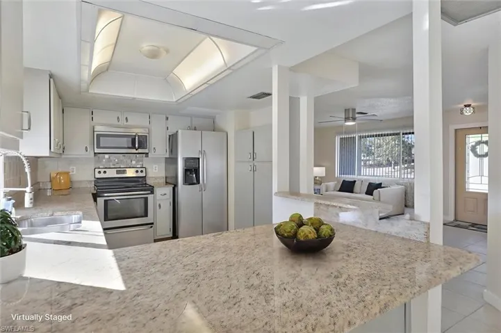 Virtually Staged Kitchen featuring stainless steel appliances, light stone countertops, a peninsula, ceiling fan, and tasteful backsplash