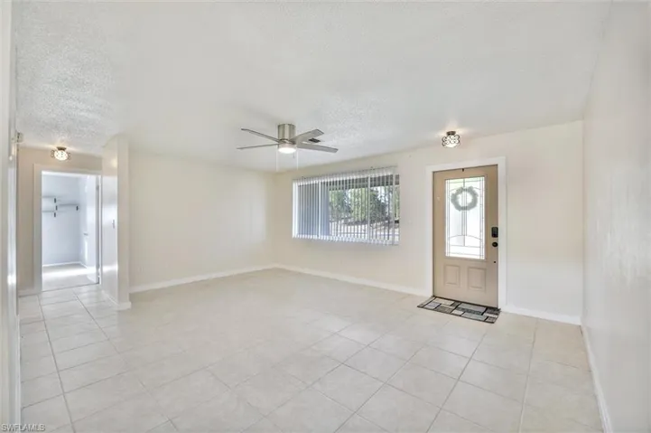 Entryway with a textured ceiling, a ceiling fan, and light tile patterned floors