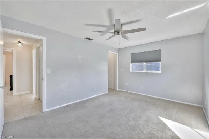Empty room featuring light carpet, a textured ceiling, and a ceiling fan