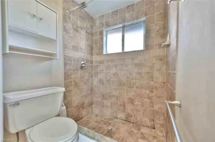 Full bath featuring toilet and tiled shower
