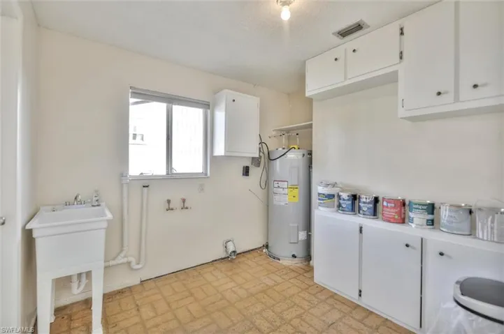 Laundry room featuring cabinet space, electric water heater, washer hookup, brick patterned flooring, and a textured ceiling