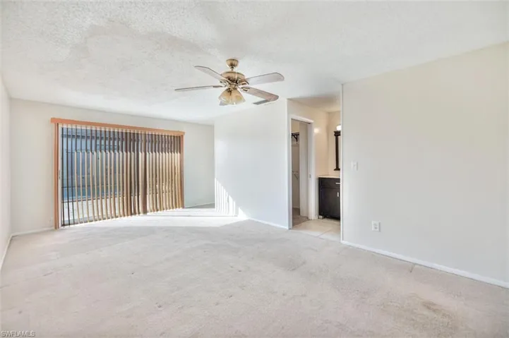 Empty room featuring a textured ceiling, a ceiling fan, and light carpet