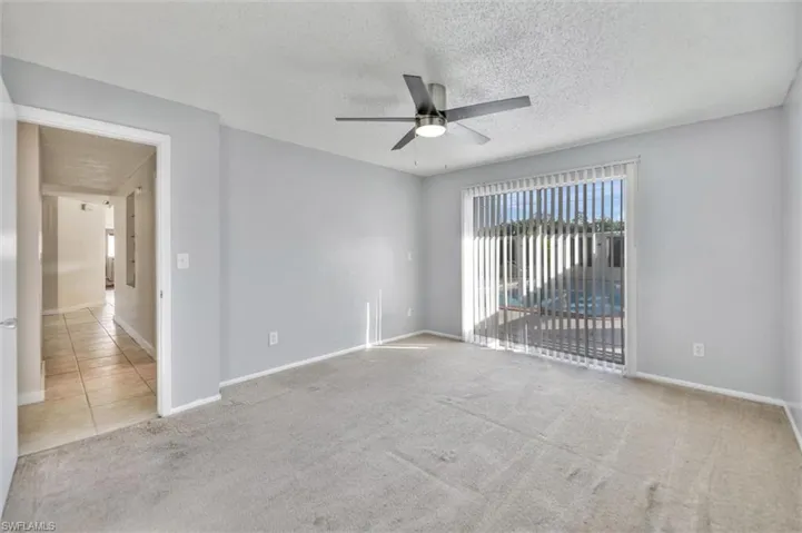Empty room featuring light carpet, a textured ceiling, and a ceiling fan