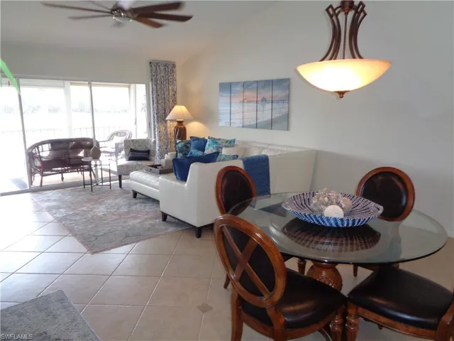 Dining area featuring light tile patterned flooring, vaulted ceiling, and a ceiling fan