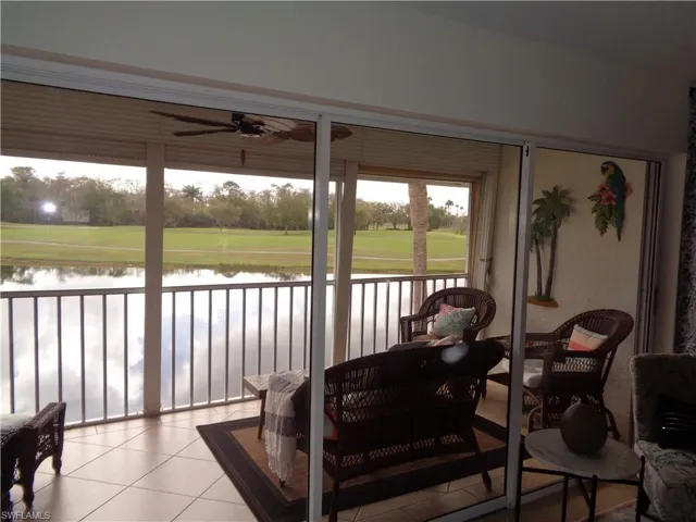 Sunroom featuring ceiling fan, view of wooded area, and a water view