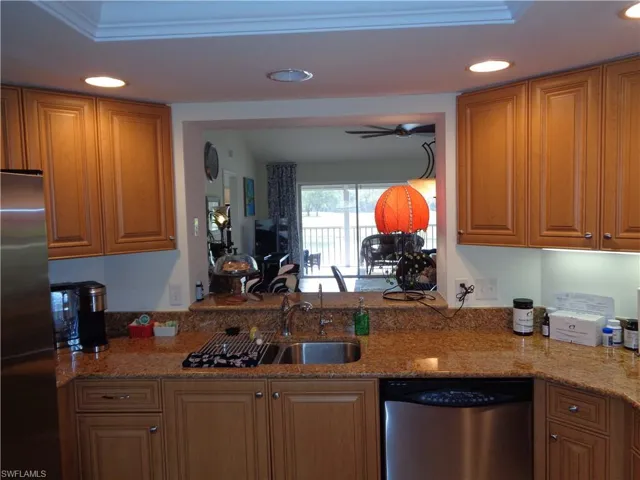 Kitchen with appliances with stainless steel finishes, recessed lighting, light stone counters, ceiling fan, and brown cabinetry