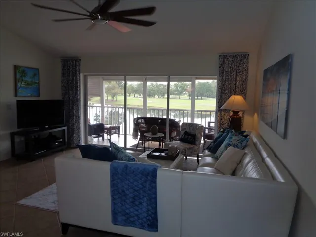 Living area with lofted ceiling, healthy amount of natural light, a ceiling fan, tile patterned floors, and a water view
