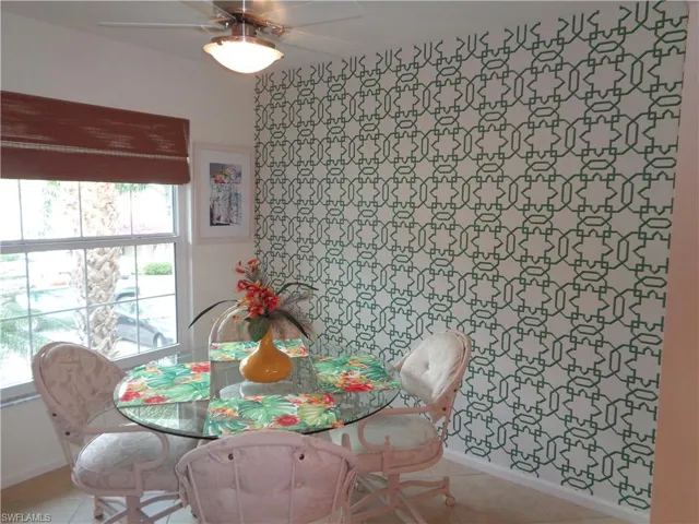 Tiled dining space with ceiling fan and baseboards
