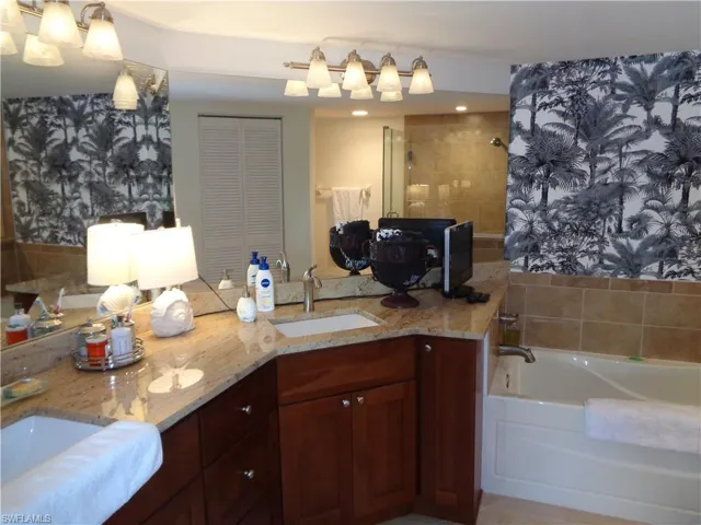 Full bathroom with double vanity, a garden tub, wallpapered walls, and a closet