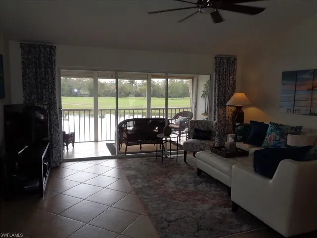 Living room with lofted ceiling, tile patterned flooring, and a ceiling fan