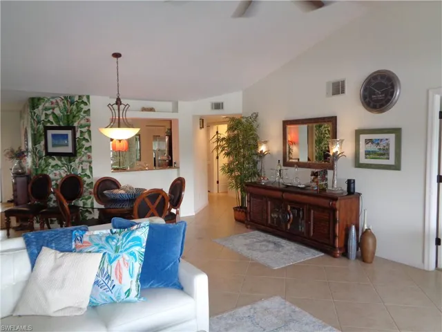 Living area featuring vaulted ceiling, tile patterned floors, and a ceiling fan