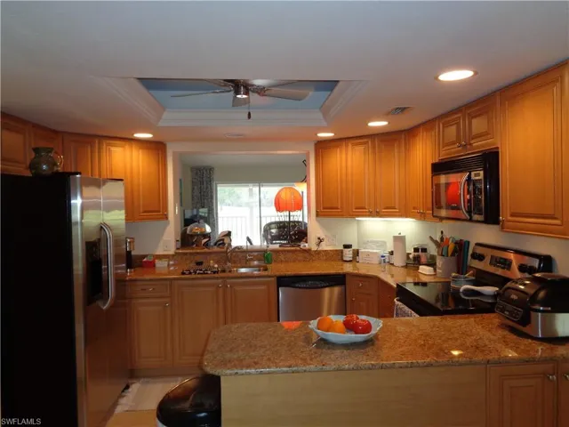 Kitchen featuring appliances with stainless steel finishes, a tray ceiling, crown molding, ceiling fan, and recessed lighting