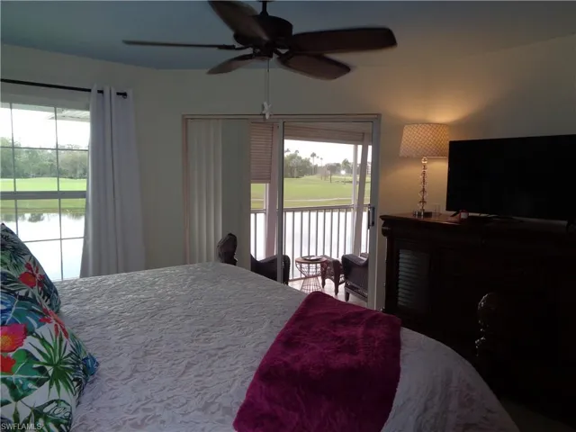 Bedroom featuring access to exterior, multiple windows, a water view, and ceiling fan