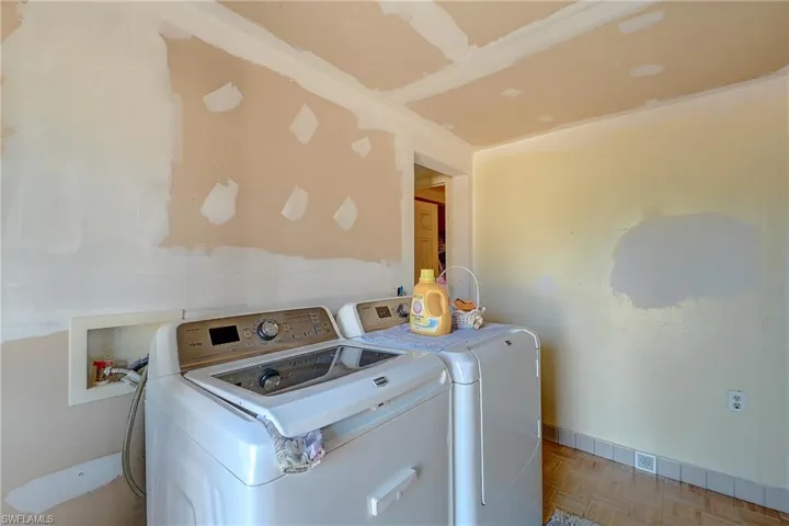 Laundry room with washing machine and clothes dryer and parquet flooring