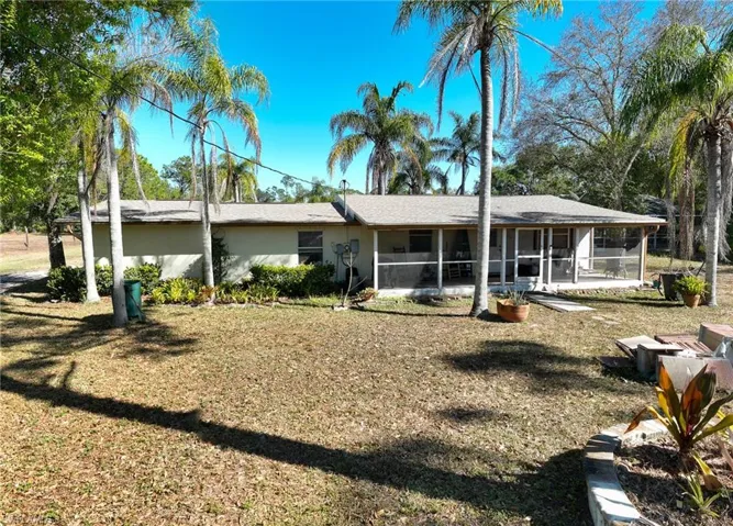Rear view of property featuring a sunroom, a yard, and stucco siding
