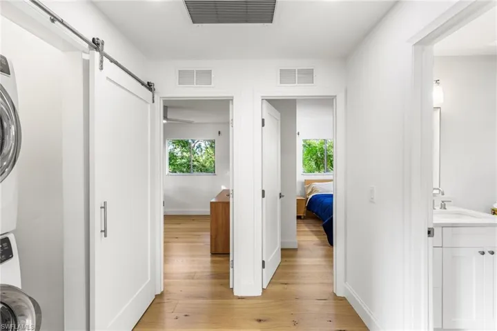 Corridor with a barn door, light wood-type flooring, and stacked washer / dryer