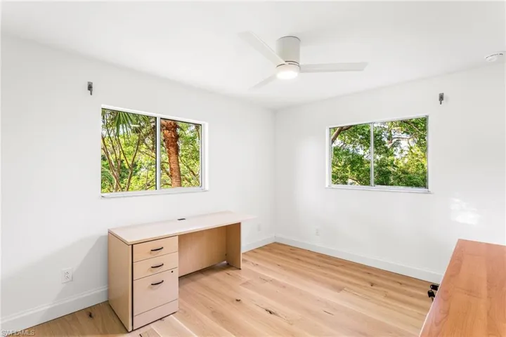 Unfurnished office featuring light wood-type flooring, healthy amount of natural light, and a ceiling fan