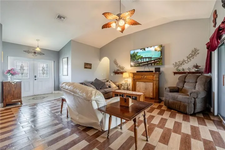 Living room with ceiling fan, hardwood / wood-style floors, and vaulted ceiling