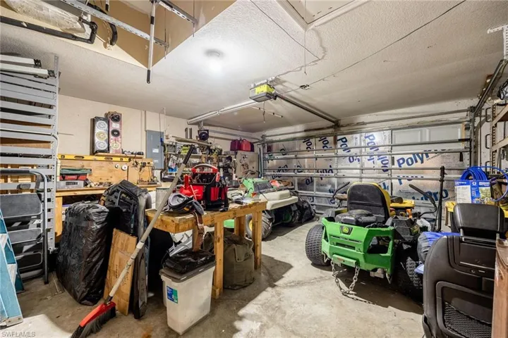 Garage featuring a workshop area, electric panel, and a garage door opener