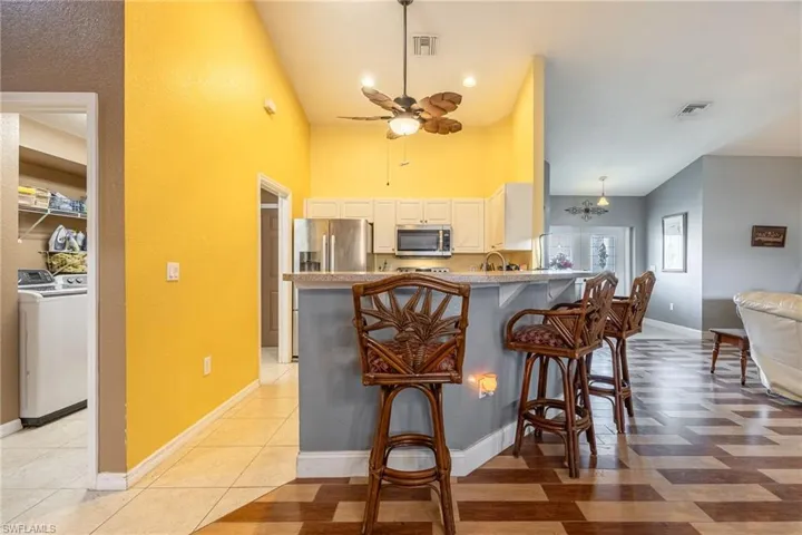 Kitchen with a breakfast bar area, ceiling fan, light tile patterned floors, kitchen peninsula, and stainless steel appliances