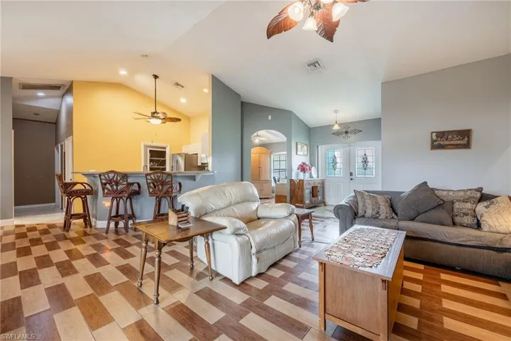 Living room featuring ceiling fan with notable chandelier and lofted ceiling