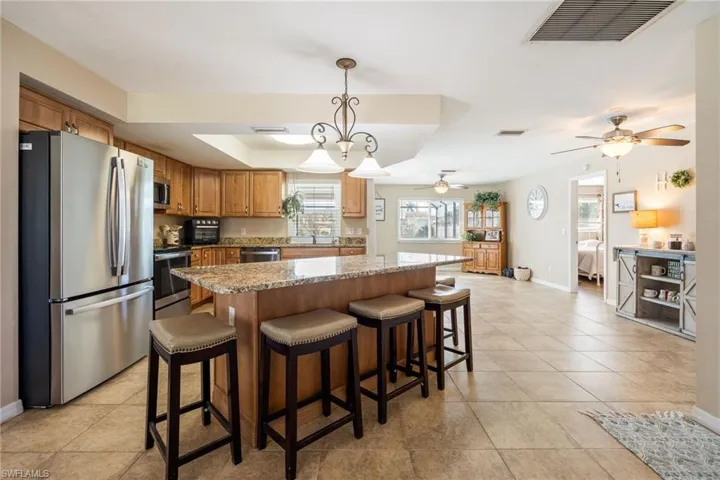 Kitchen with pendant lighting, appliances with stainless steel finishes, light stone counters, a center island, and a kitchen breakfast bar
