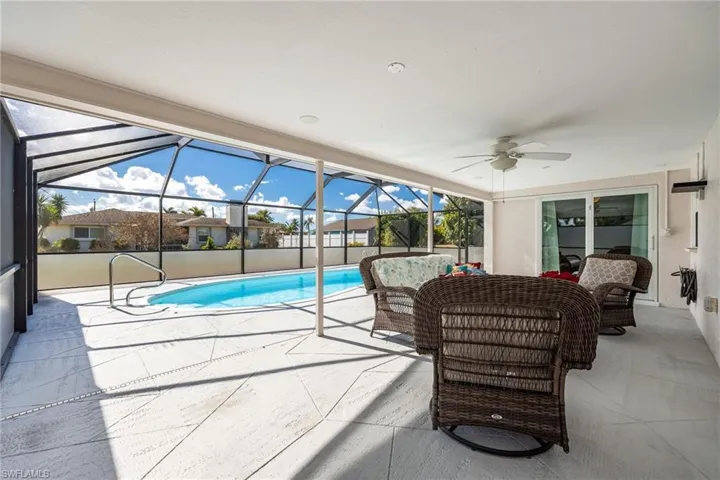 Outdoor pool featuring a patio area, a sunroom, glass enclosure, and an outdoor hangout area