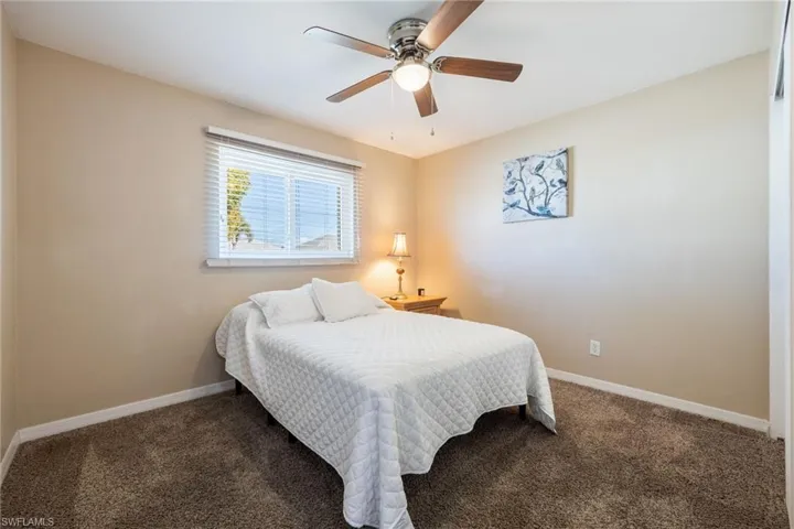 Carpeted bedroom featuring baseboards and ceiling fan