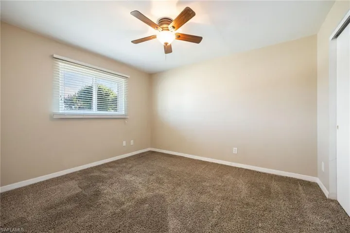 Carpeted empty room featuring baseboards and a ceiling fan