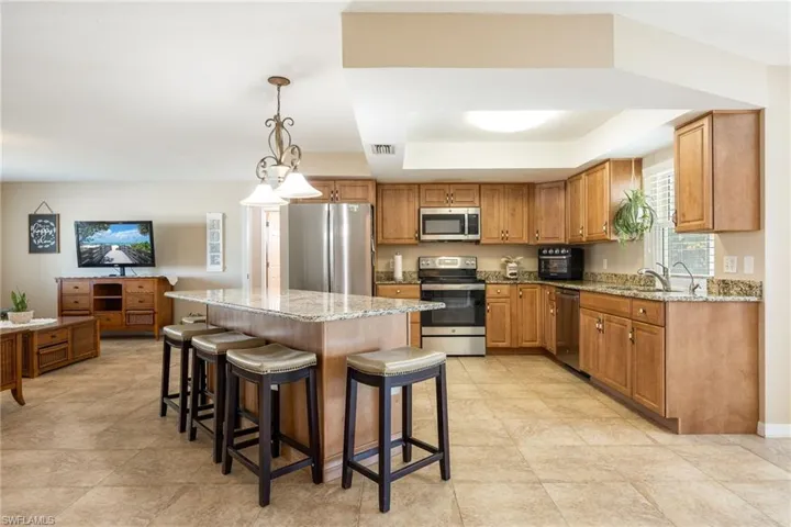 Kitchen with light stone countertops, brown cabinets, a kitchen breakfast bar, and appliances with stainless steel finishes