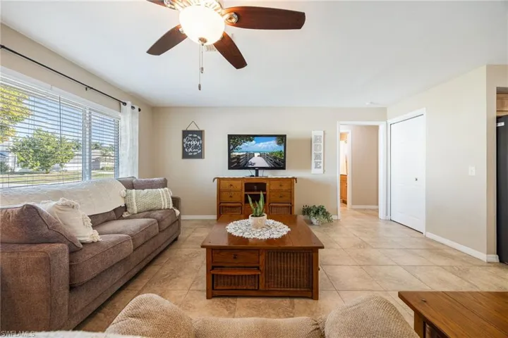 Living room with a ceiling fan and light tile patterned floors