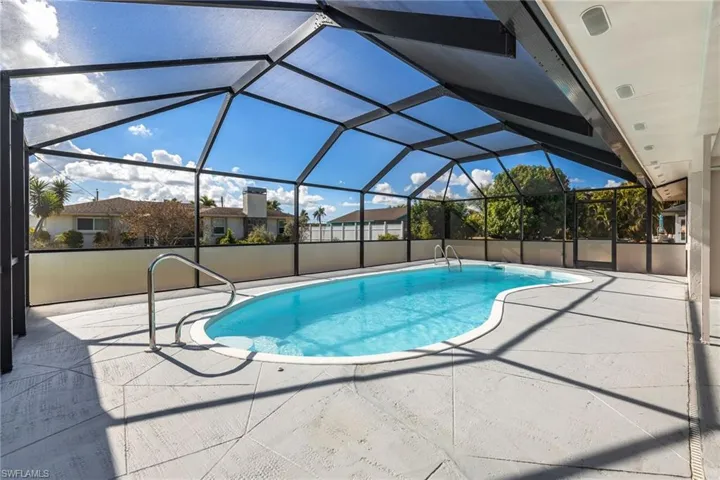 Swimming pool with glass enclosure, a sunroom, and a patio area