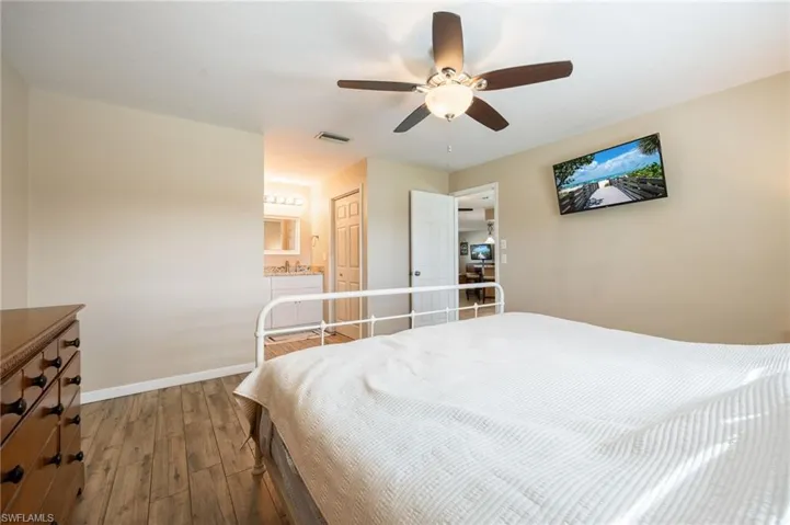 Bedroom featuring wood-type flooring, a ceiling fan, ensuite bathroom, and a closet