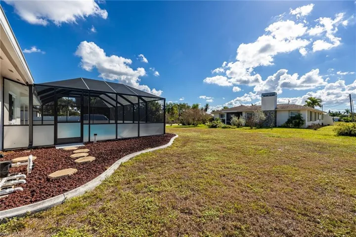 View of green lawn with a lanai and a sunroom
