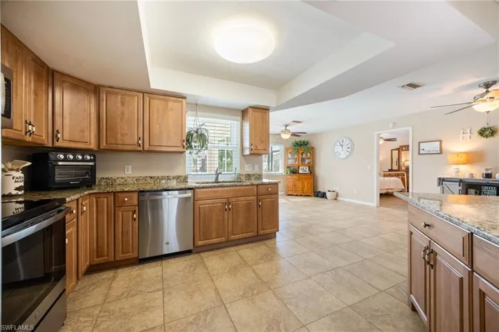Kitchen with a tray ceiling, dark stone counters, and brown cabinets