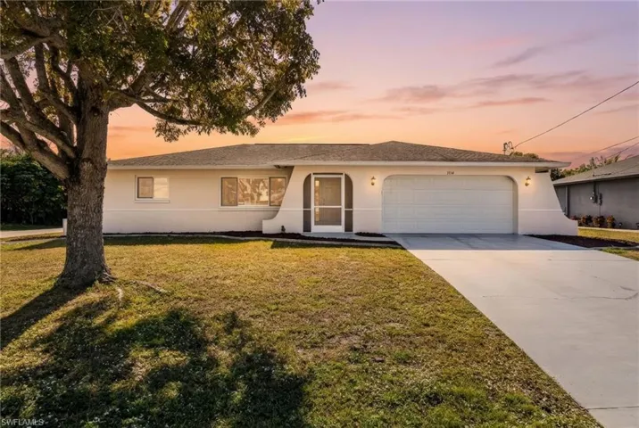 View of front facade featuring stucco siding, driveway, and a front yard