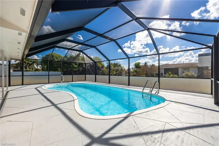 Swimming pool with glass enclosure, a sunroom, and a patio
