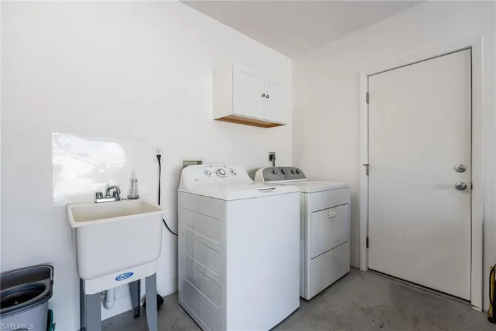 Laundry room featuring concrete flooring, washer and dryer, and cabinet space