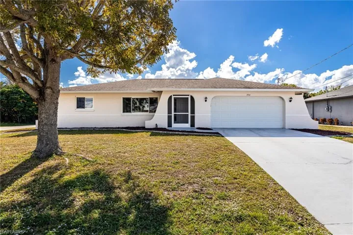Ranch-style house featuring stucco siding, concrete driveway, a front yard, and a garage