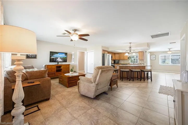 Living area featuring a ceiling fan, a chandelier, and light tile patterned flooring