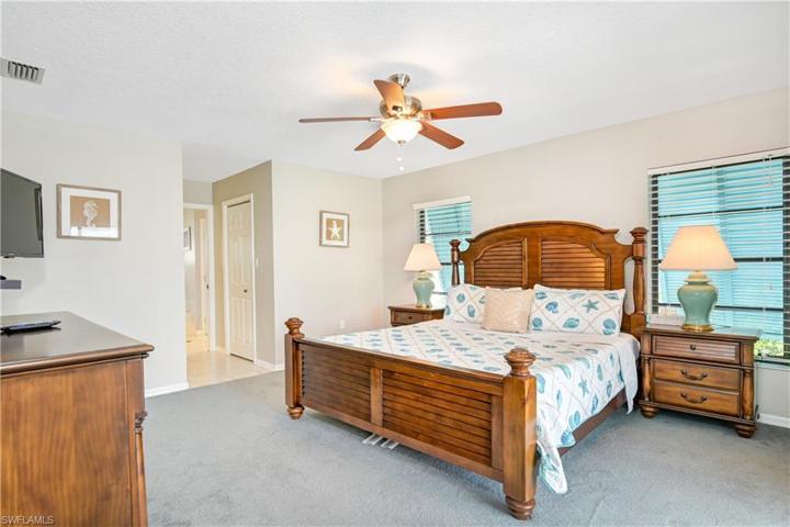 primary bedroom with king bed, ensuite bath, and sliders to the lanai and pool - 2 walk-in closets